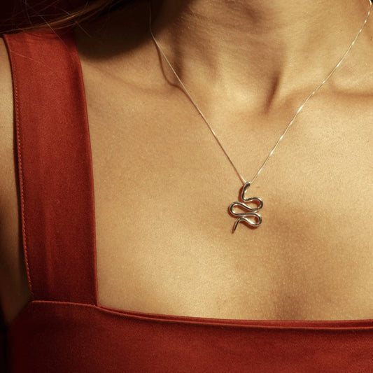 Silver 950 Mamba snake pendant necklace on a woman's chest with a rust-colored top.