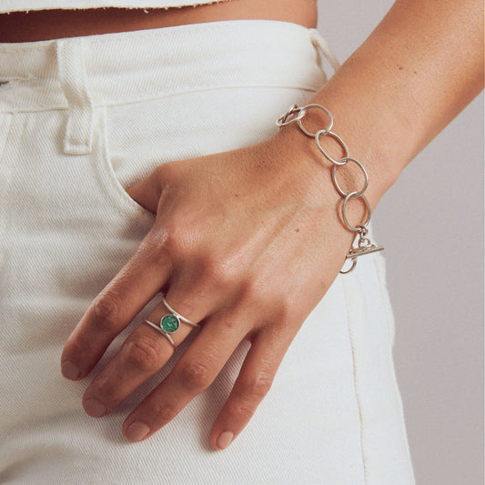 Silver 950 double-band ring with a round emerald, worn with a matching link bracelet.