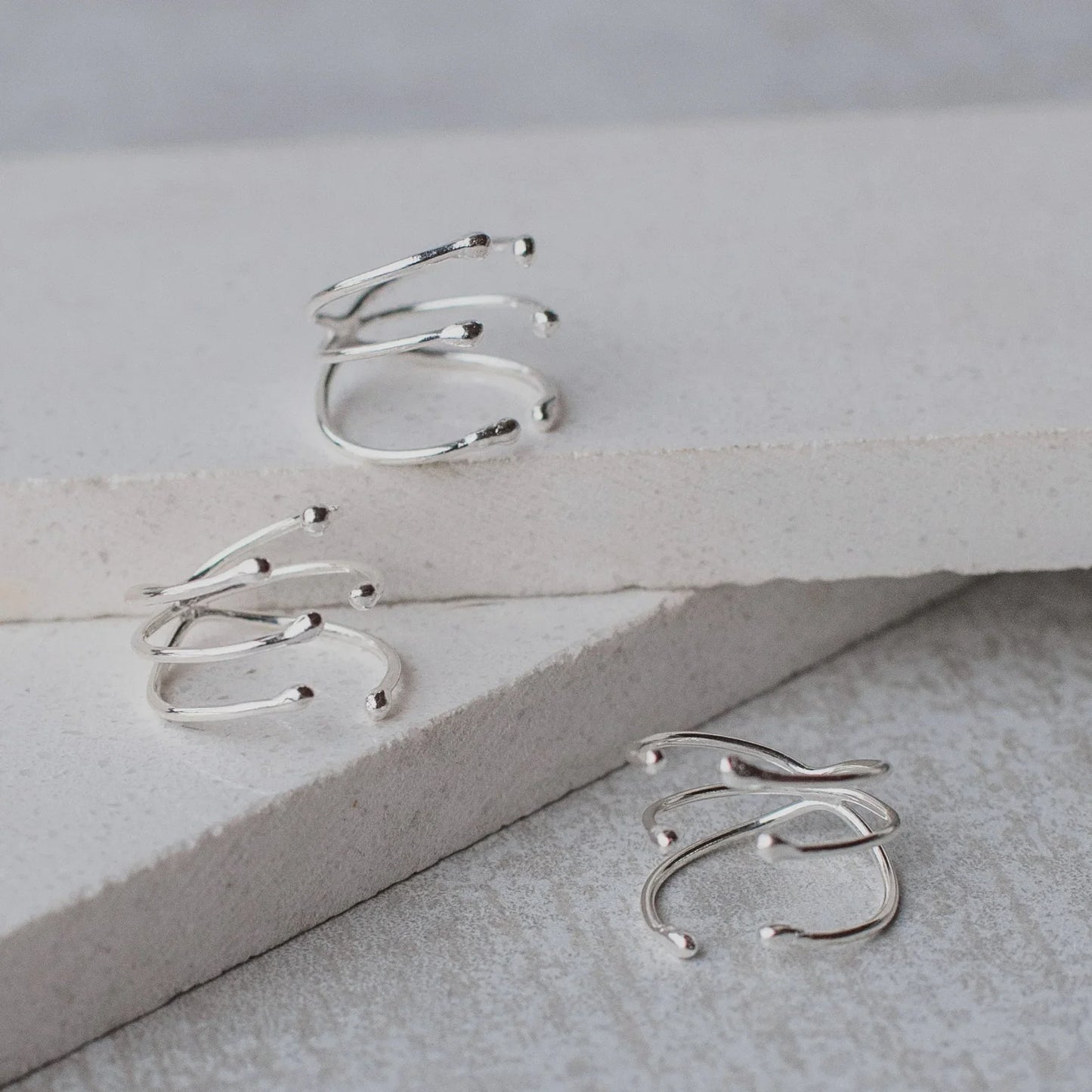 Three shiny silver Manglar rings with a unique, multi-band branch-like design on white surfaces.