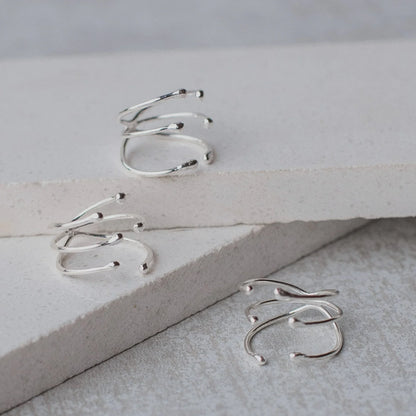 Three shiny silver Manglar rings with a unique, multi-band branch-like design on white surfaces.