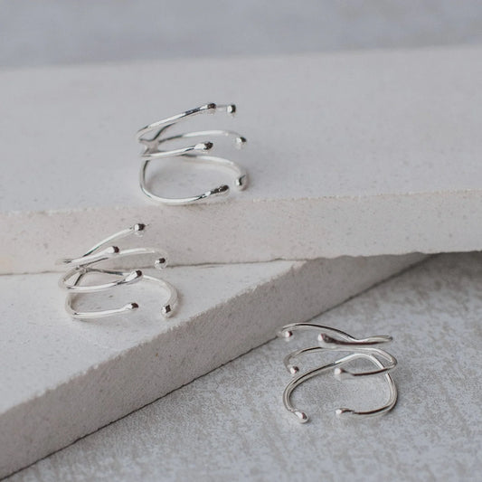Three shiny silver Manglar rings with a unique, multi-band branch-like design on white surfaces.