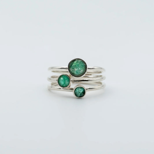 Three handcrafted recycled silver rings, each with a vibrant round Colombian emerald.