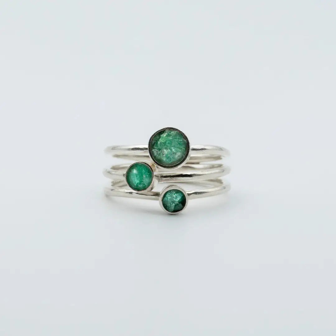 Three handcrafted recycled silver rings, each with a vibrant round Colombian emerald.