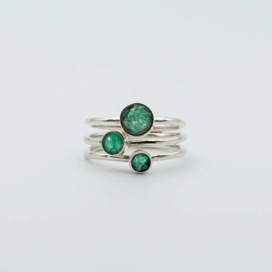 Three handcrafted recycled silver rings, each with a vibrant round Colombian emerald.