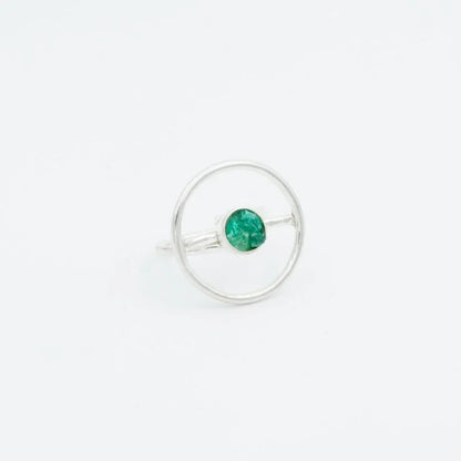 Silver ring with a raw green Colombian emerald set within a modern circular design.