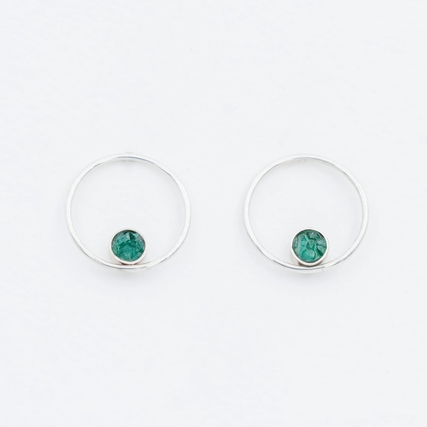 Pair of handmade silver hoop earrings with small, raw Colombian emerald stones.