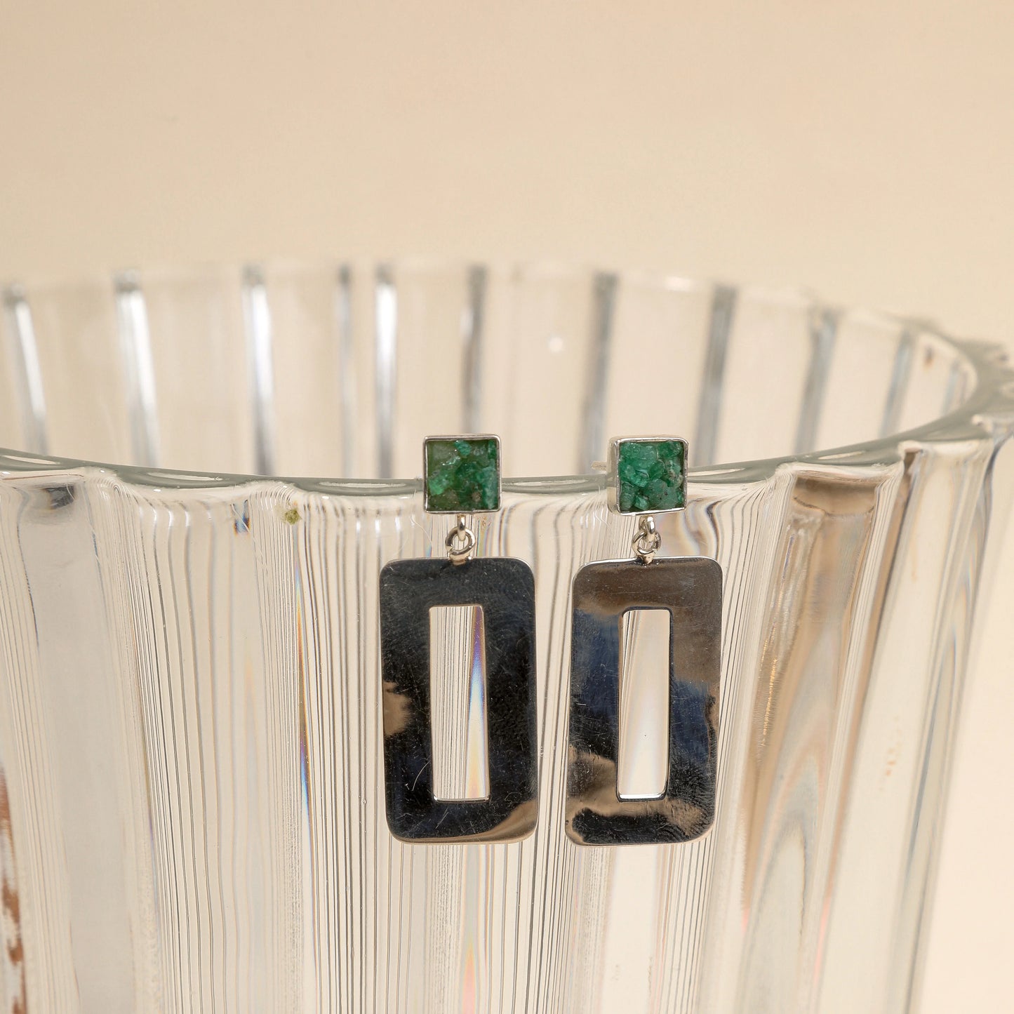 Silver dangle earrings with square emerald studs and rectangular open frames.