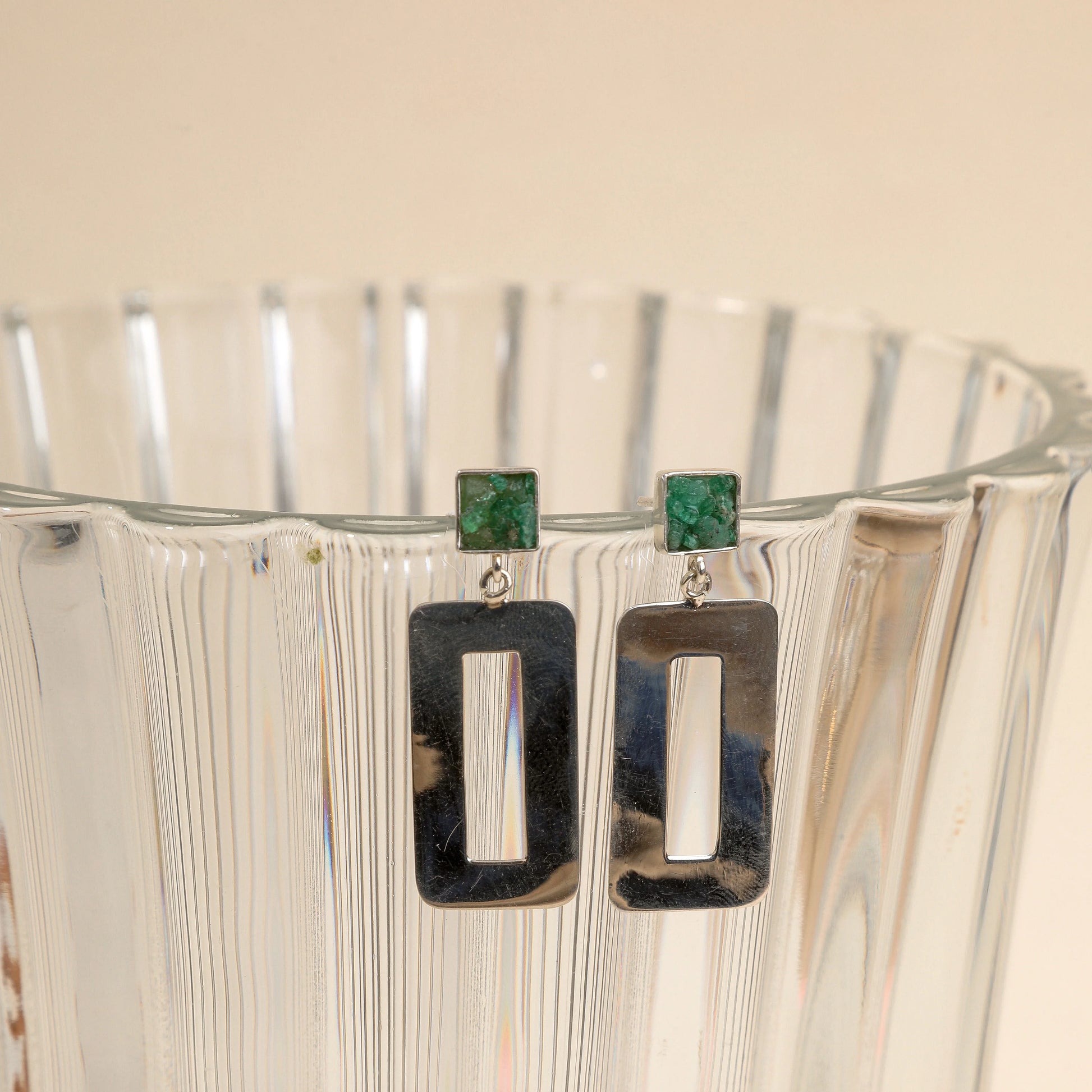 Silver dangle earrings with square emerald studs and rectangular open frames.