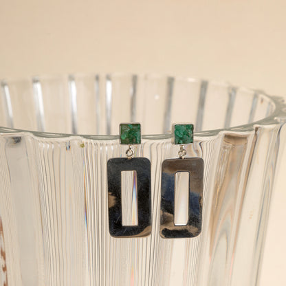 Silver dangle earrings with square emerald studs and rectangular open frames.