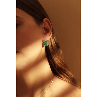Silver 950 square emerald stud earring on a woman's ear, with a silver chain necklace.