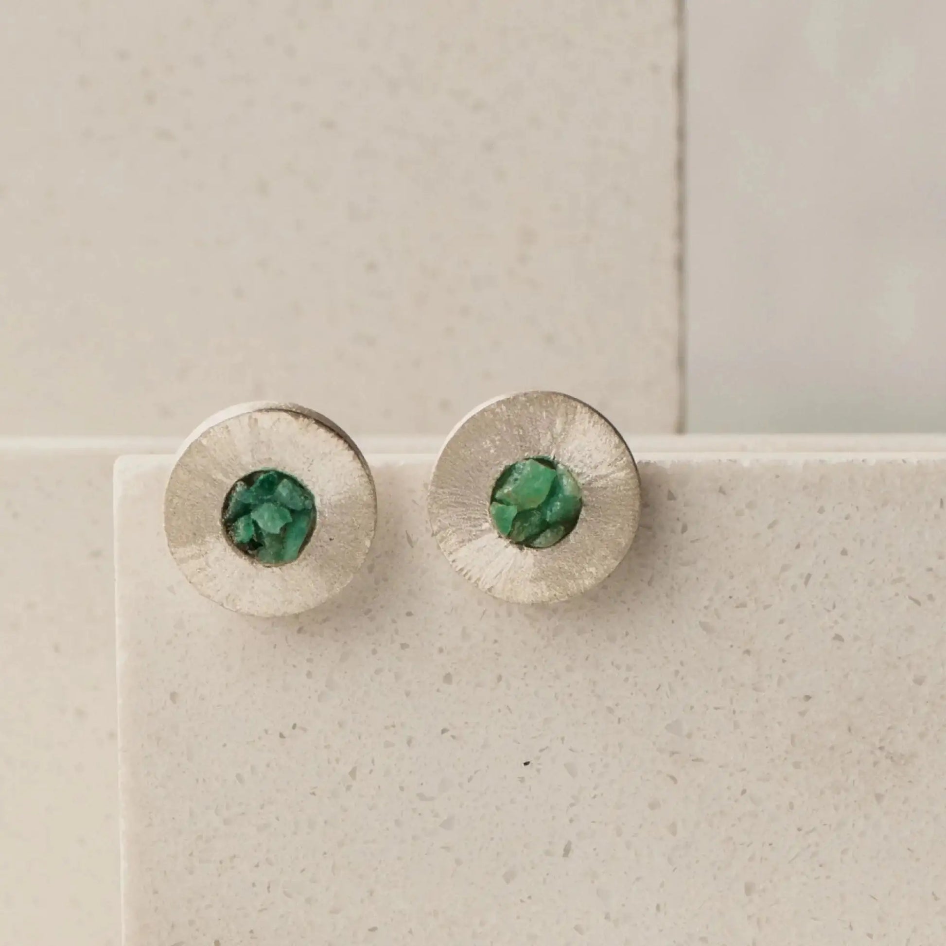 Round textured recycled silver stud earrings with raw Colombian emerald centers.