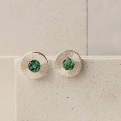 Round textured recycled silver stud earrings with raw Colombian emerald centers.