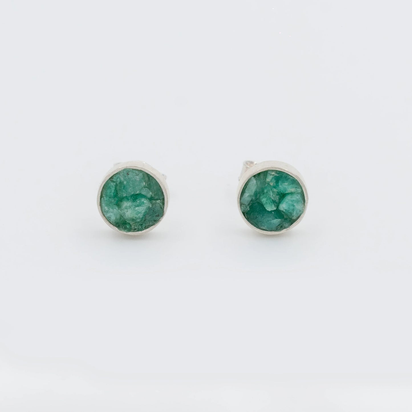Handmade circular sterling silver 950 stud earrings with raw Colombian emeralds.