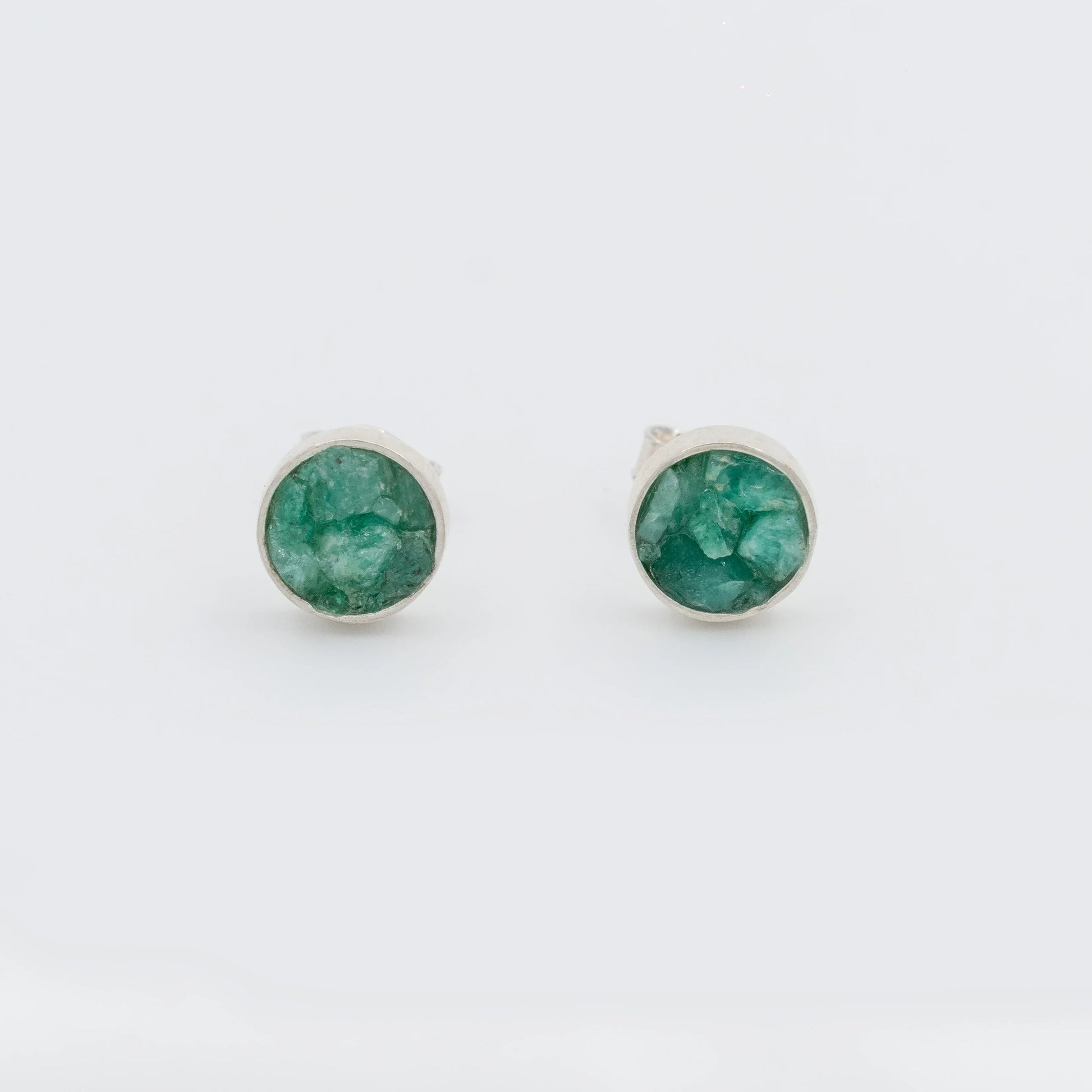Handmade circular sterling silver 950 stud earrings with raw Colombian emeralds.