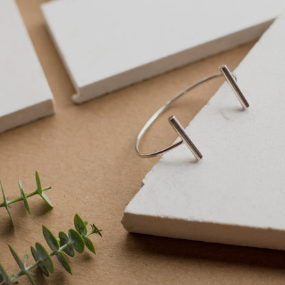 Sleek silver 950 cuff bracelet with two parallel bar ends, displayed on white blocks.