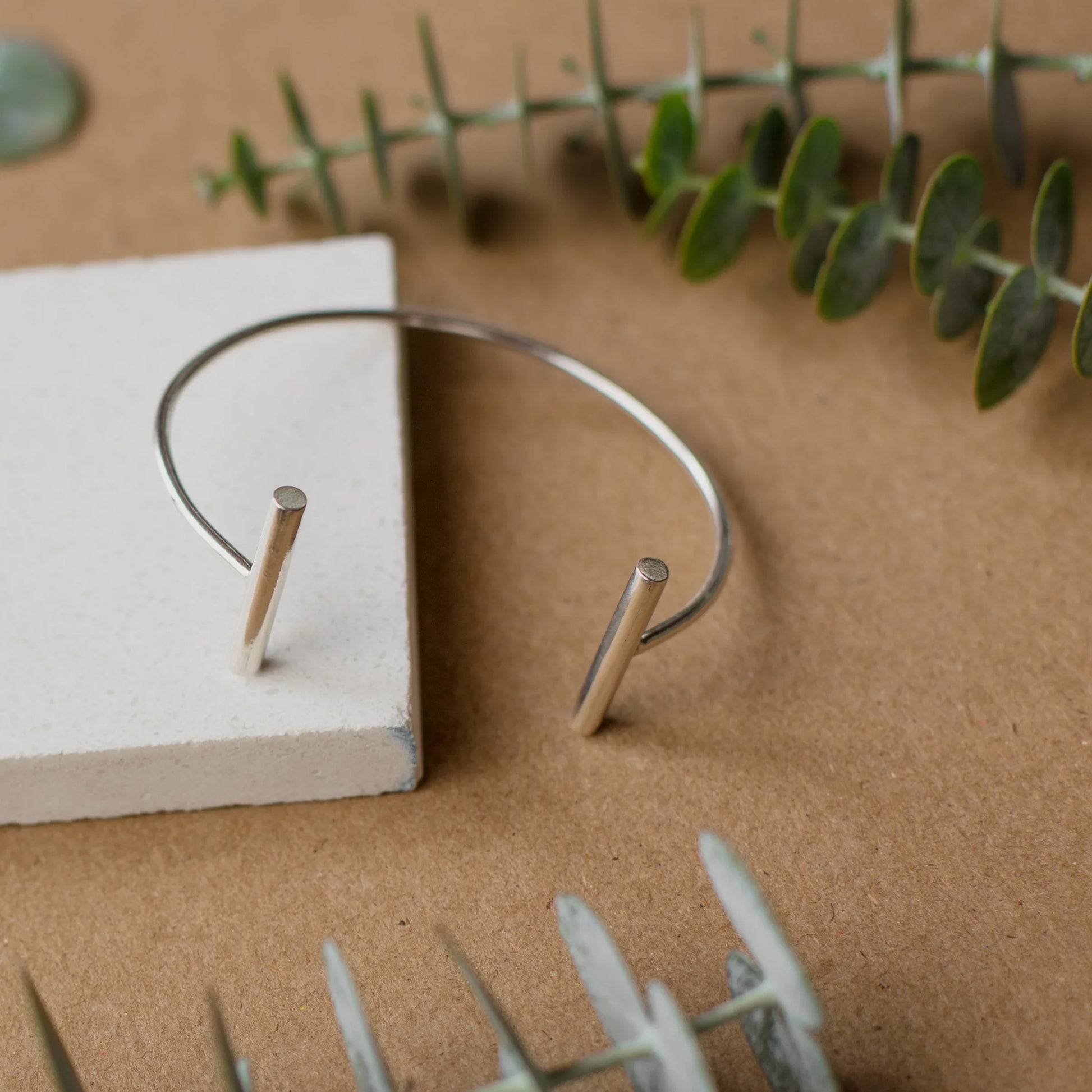 Sleek silver 950 cuff bracelet with two minimalist bar ends, on a natural background.