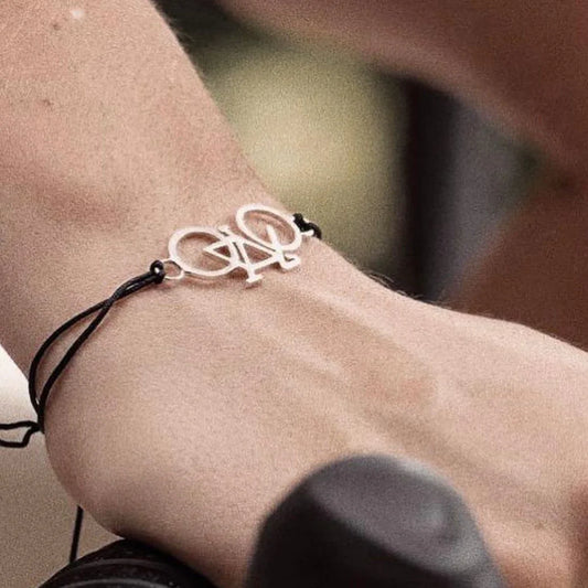 Silver 950 bicycle charm bracelet with black cord on a wrist.