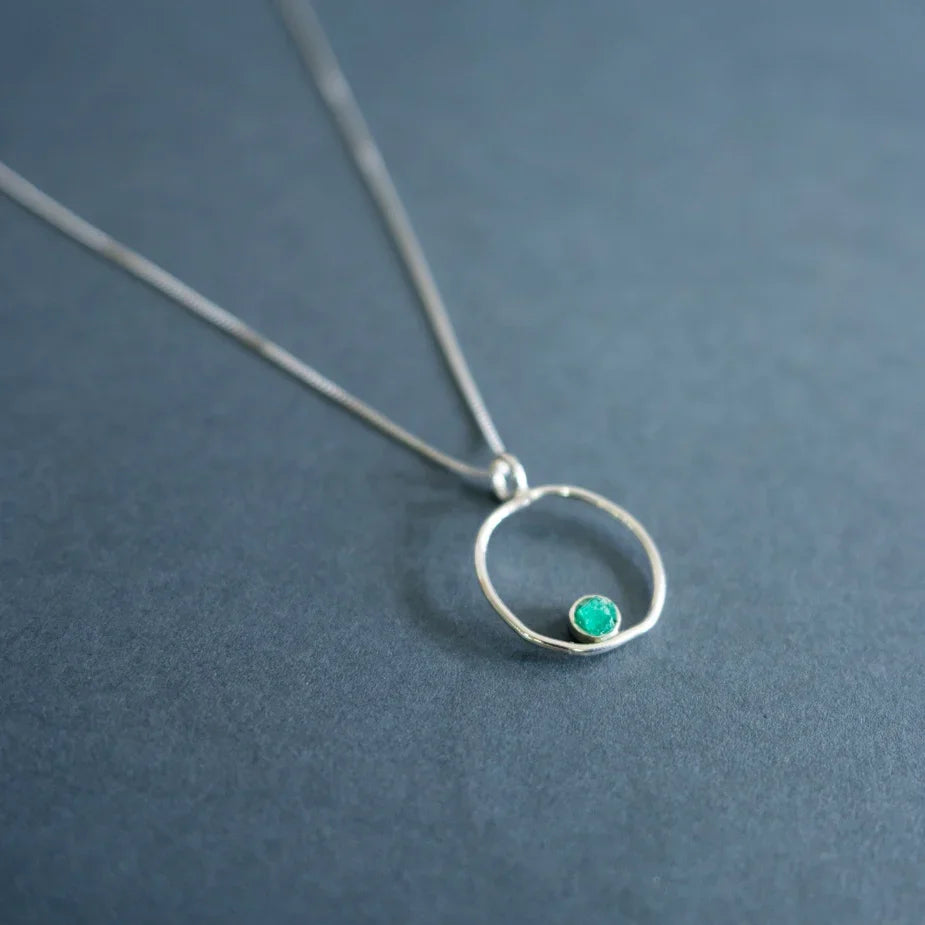 Silver 950 necklace with a delicate open circle pendant and a small, vibrant Colombian emerald.