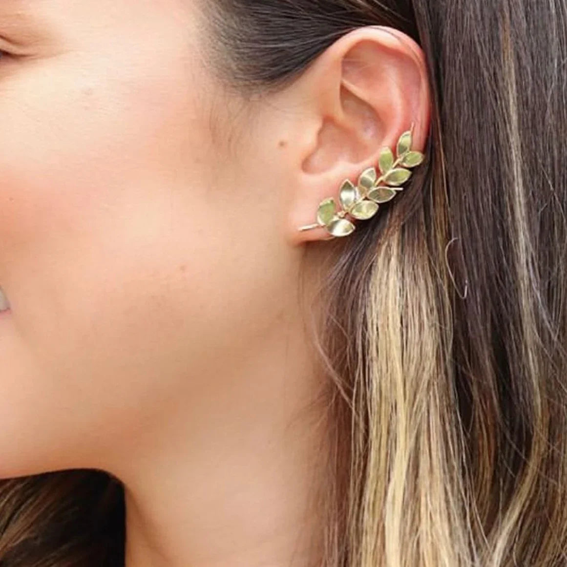 Gold-plated 950 silver ear cuff with a delicate leaf design, worn on a woman's ear.