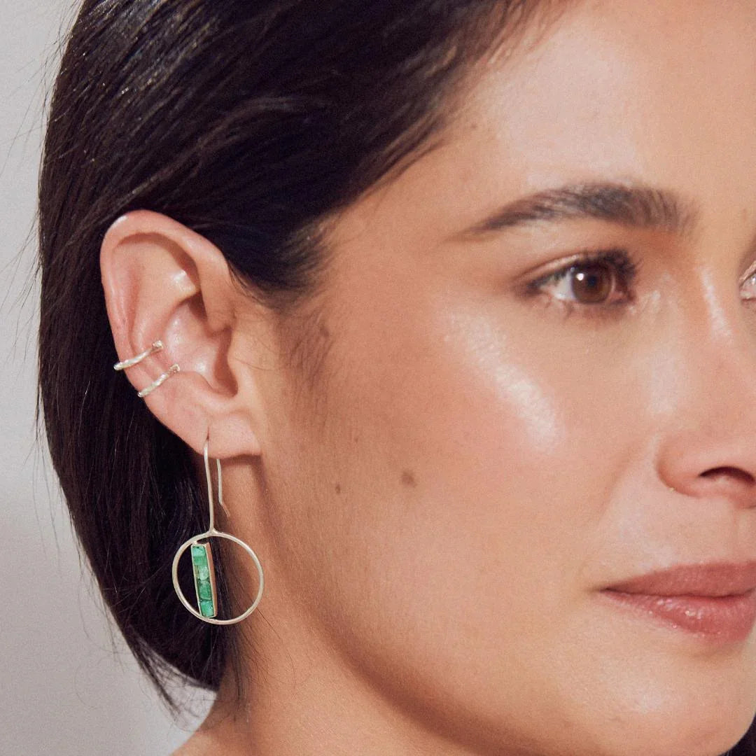 Silver 950 hoop earring with a rectangular Colombian emerald bar, worn by a woman.