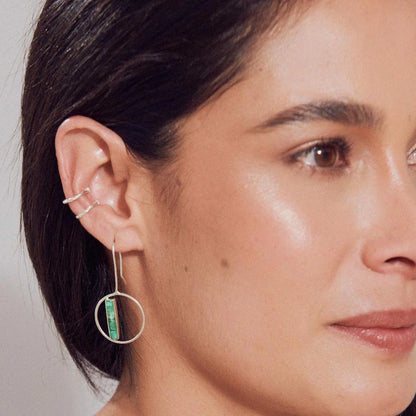 Silver 950 hoop earring with a rectangular Colombian emerald bar, worn by a woman.