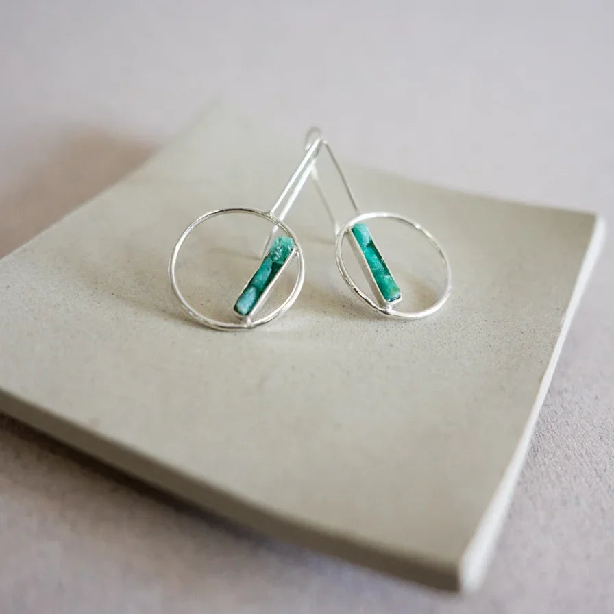 Silver 950 hoop earrings with rectangular Colombian emerald bars, displayed on a light gray surface.